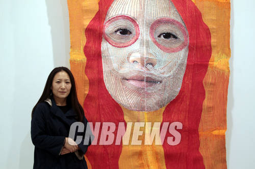 일우스페이스 전시장에서 자신의 누더기 얼굴 작품과 함께한 윤지선 작가.(사진=왕진오 기자)