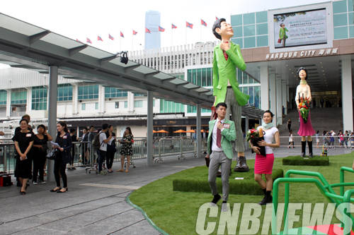 조각가 김경민이 5월 15일부터 6월 2일까지 홍콩에 위치한 갤러리 바이 하버에서 진행하는 개인전 'Happy Moments'에 설치된 대형 조각품 앞에서 작품의 모습을 따라하고 있는 퍼포머들.(사진=선컨템포러리)