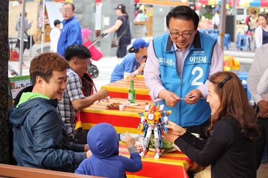 이인재 파주시장 후보가 주말을 맞아 나들이 나온 한 가족에게 명합을 건네고 있다.