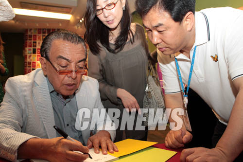 28일 서울 소공동 롯데백화점 본점 롯데갤러리에서 진행된 '브라질 만화의 거장, 마우리시우 지 소우자' 특별전 설명회에 함께한 만화가 마우리시우 지 소우자가 자신이 만들어낸 캐릭터 모니카를 취재진들에게 그려주고 있다.(사진=왕진오 기자)