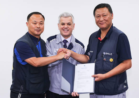 세르지오 호샤 한국지엠 사장(중앙)과 강두순 전국금속노동조합 부위원장(왼쪽), 정종환 전국금속노동조합 한국지엠 지부장(오른쪽)이 임단협 합의서에 서명 후 서로 손을 맞잡고 있다(사진 제공: 한국지엠)
