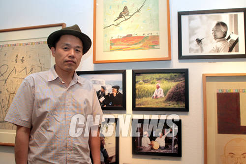 2일 오후 서울 소공동 롯데백화점 본점 롯데갤러리에서 이청준 김선두의 고향읽기 전시 설명회가 열렸다. 이날 함께한 김선두 작가가 고 이청준 작가의 사진앞에서 포즈를 취하고 있다.(사진=왕진오 기자)