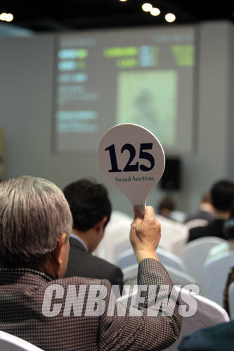 23일 오후 4시부터 서울 평창동 서울옥션 본사에서 진행된 제133회 경매에 한 응찰자가 경매 낙찰을 위해 패드를 들고 있다.(사진=왕진오 기자)