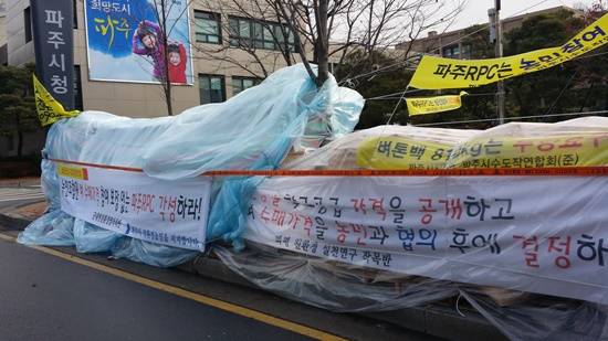 파주시 친화경 농업인들의 파주시청 앞 천막농성 9일 째, 비와 눈으로 비닐 천막과 벼를 담은 비닐이 늘어져 있다.