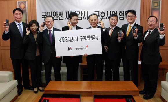민간주도 국민안전체계 구축을 위한 KT와 대한적십자사간 협약 체결식에서 참석자들이 라져 1 단말기를 들고 포즈를 취하고 있다. 왼쪽부터 대한적십자사 김상진 인도주의 사업본부장, 손정희 사업추진국장, 강호권 사무총장, 김성주 총재, KT 황창규 회장, 윤경림 미래융합사업추진실장, 박윤영 미래사업개발단장, 오영호 홍보실장(사진 제공: KT)