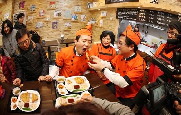 21일 오후 수원 조원시장 내 사회적협동조합 마돈나돈가스에서 남경필 경기도지사와 이기우 경기도 사회통합부지사가 만든 돈가스를 직접 손님에게 서빙을 하고 같이 시식을 하고 있다(사진=경기도 제공)