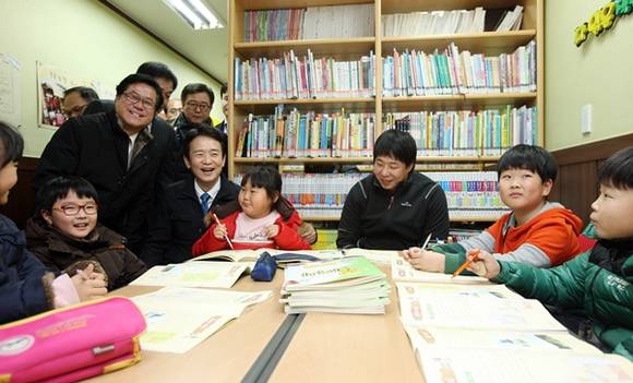 수원 조원시장 내 마을공동체 대추동이 작은도서관을 찾은 남경필 경기도지사와 이기우 경기도 사회통합부지사가 시설 내에서 운영되고 있는 공부방의 자원봉사자 및 학생들과 이야기를 나누고 있다(사진=경기도 제공)