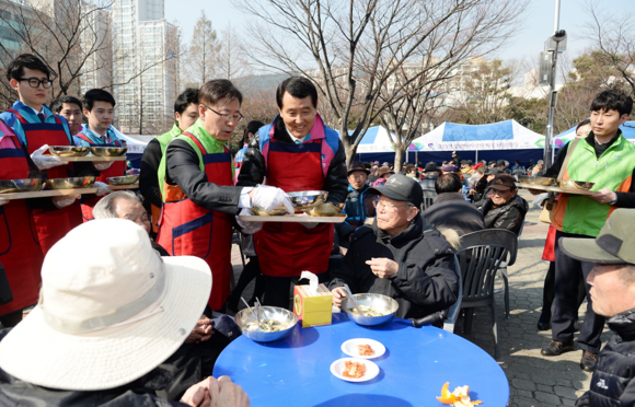 성세환 BS금융그룹 회장(가운데)과 김재천 주택금융공사 사장이 11일 부산시청 녹음광장에서 설을 앞두고 어르신들에게 떡국을 직접 대접하고 있다.