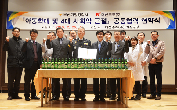 25일 기장 대선주조 생산공장에서 박진배 대선주조 대표(가운데 오른쪽)와 안정용 기장경찰서장(가운데 왼쪽)이 협약서를 들고 양측 관계자들과 함께 4대 사회악 근절 협력을 약속했다. (사진제공=대선주조)