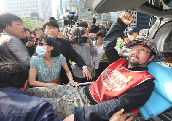 서울 소공동 서울중앙우체국 옆 광고탑에서 80일간 고공농성을 벌인 강세웅 LGU유플러스 비정규직지부 조직부장이 26일 오후 고공농성을 종료한 뒤 광고탑에서 내려와 구급차에 타고 있다.(사진: 연합뉴스)
