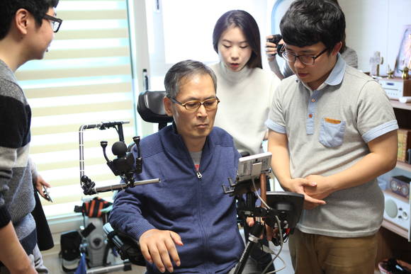 장애인 육근홍 씨가 손이나 팔이 불편한 장애인들이 스마트폰을 사용할 수 있도록 도와주는 앱을 보고 있다.