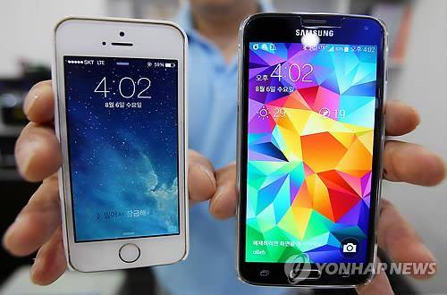 2014년 8월 서울 시내 한 휴대전화 매장에서 직원이 아이폰5s(왼쪽)과 갤럭시S5를 들고 있는 모습(사진: 연합뉴스)