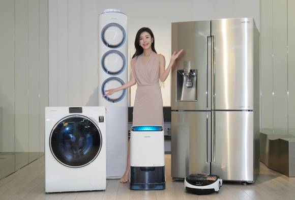 삼성전자 모델이 18일 삼성전자 수원사업장 생활가전동 프리미엄 하우스에서 ‘인버터 컴프레서’와 ‘인버터 모터’의 무상보증 기간이 10년으로 일원화된 삼성 생활가전 제품들을 소개하고 있다. 왼쪽부터 시계방향으로 WW900 세탁기, 스마트에어컨 Q9000, 셰프컬렉션 냉장고, 파워봇 로봇청소기, 2015년형 인버터제습기(사진 제공: 삼성전자)