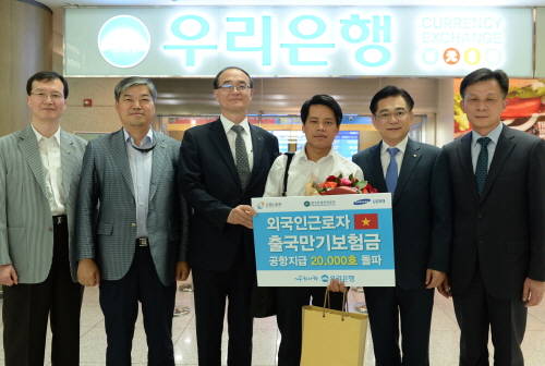17일 우리은행 인천국제공항 환전소에서 최정훈 외환사업단 상무(사진 오른쪽 두번째)가 외국인근로자 출국만기보험금 2만 번째 주인공인 베트남 출신의 누엔 만하씨를 축하한 뒤 산업인력공단 관계자들과 기념촬영을 하고 있다. (사진제공=우리은행)