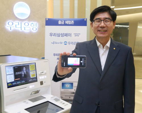 이광구 우리은행장이 20일 MST 방식을 적용한 스마트폰 ATM 현금출금이 가능한 ‘우리삼성페이’를 시현하고 있다. (사진제공=우리은행)