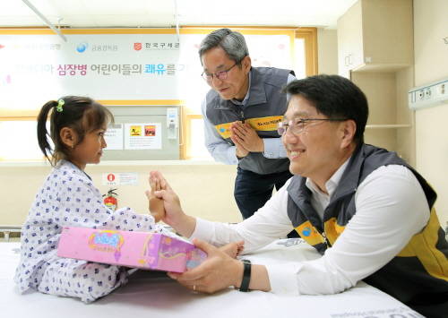 진웅섭 금융감독원장(오른쪽)이 아이에게 선물을 전달하고, 윤종규 은행장이 캄보디아식 손인사를 하고 있다. (사진제공=국민은행)