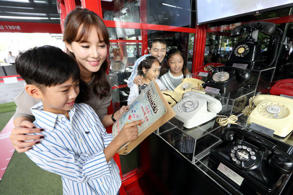 관람객들이 광화문 KT 올레스퀘어 야외 행사장에서 모스 전신기, 자석식 전화기, 수동식 교환기, 삐삐, 시티폰, 카드식 공중전화, 하이텔(PC 통신) 등 과거를 되돌아보는 전시물을 살펴보고 있는 모습. (사진제공=KT)