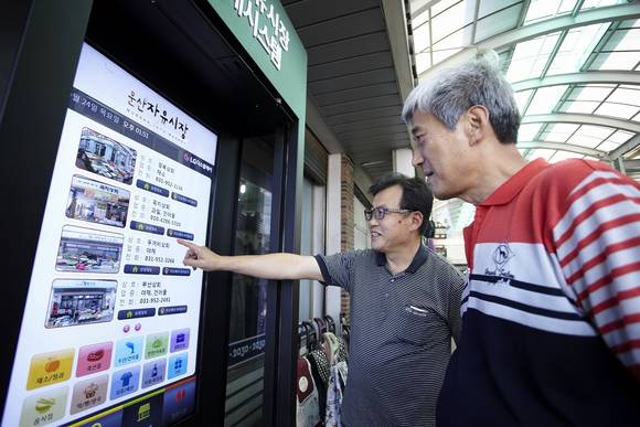 추석 명절을 앞두고 문산자유시장을 찾은 손님들이 LG디스플레이의 47인치 커머셜 디스플레이를 통해 시장, 상점 등 다양한 정보를 둘러보고 있다. (사진제공=LG디스플레이)