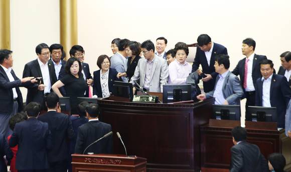 여야 의원들이 엉켜 아수라장이 된 경기도의회 단상. 의원들의 몸싸움으로 옆에 있던 태극기가 쓰러질뻔하자 의회 직원들이 옆으로 태극기를 치우는 어이없는 일까지 벌여졌다. (사진=연합뉴스)