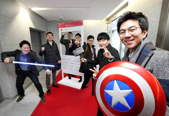 K뱅크 준비법인 직원이 레드카펫과 SNS 포토월을 배경으로 히어로 소품을 들고 기념촬영을 하고 있다. (사진제공=KT)