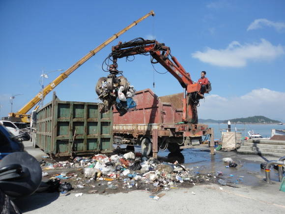 목포시가 북항 물양장에 쌓여 있는 해양쓰레기를 장비를 동원해 치우고 있다.