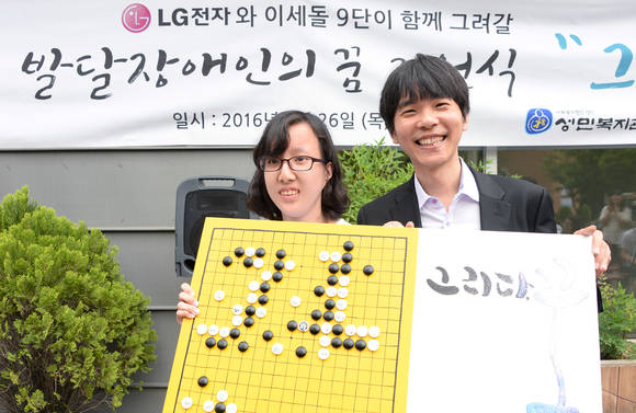 성민직업대학 학생이 인공지능과 이세돌 9단의 대국에서 ‘신의 한 수’로 평가받고 있는 기보를 직접 그린 그림을 선물하고 있다. (사진제공=LG전자)