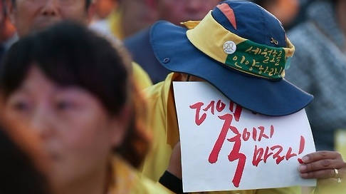 지난 26일 경찰이 세월호 유가족의 특조위 활동 농성장을 강제 철거하면서 손혜원‧박주민 더불어민주당 의원이 직접 행동에 나서 눈길을 끈다. 사진은 전날 서울 광화문광장에서 열린 ‘세월호특별법 개정 촉구 범국민문화제’에서 한 참가자가 고개를 숙인 채 피켓을 들고 있는 모습. (사진=연합뉴스)