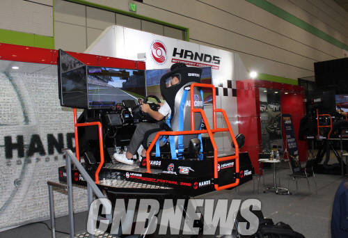 핸즈코퍼레이션 부스에서 체감형 레이싱 시뮬레이터를 즐기는 참관객들. (사진=정의식 기자)