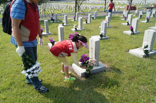 롯데건설 임직원 봉사단인 한 어린이가 묘역단장을 하고 있는 모습. (사진=롯데건설)